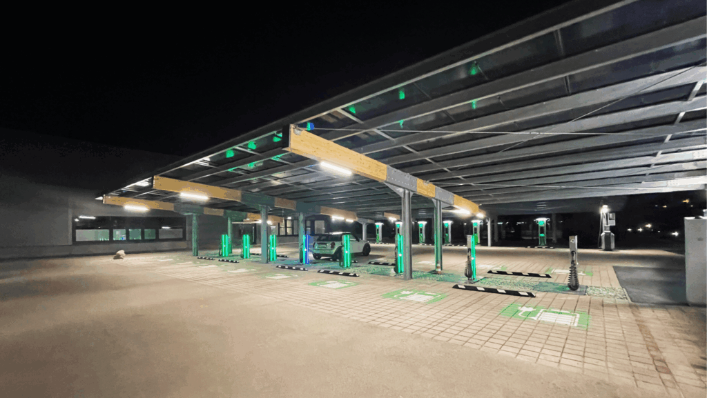 Nachtszene eines Solarcarports mit mehreren freien Ladeplätzen, beleuchteten E-Ladestationen und einem geparkten Elektrofahrzeug.