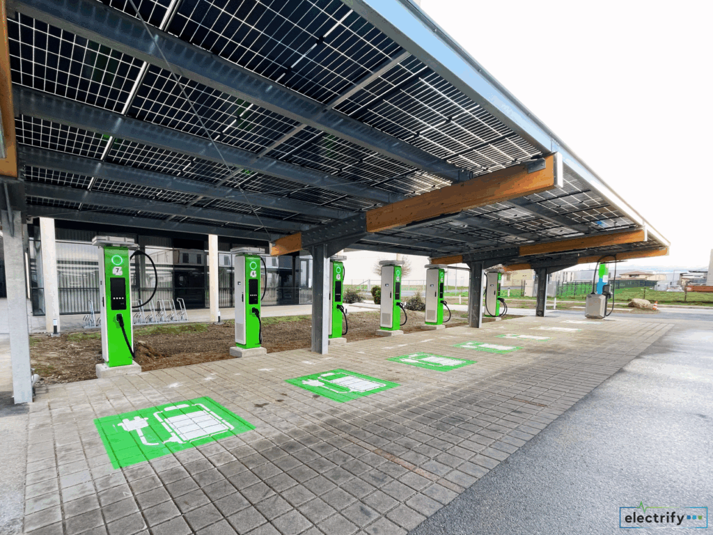 Tagesaufnahme eines Solarcarports mit grünen Ladesäulen und aufgemalten Ladeplätzen für Elektroautos.