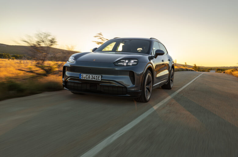 Der vollelektrische Porsche Cayenne Electric fährt auf einer Landstraße bei Abendlicht.