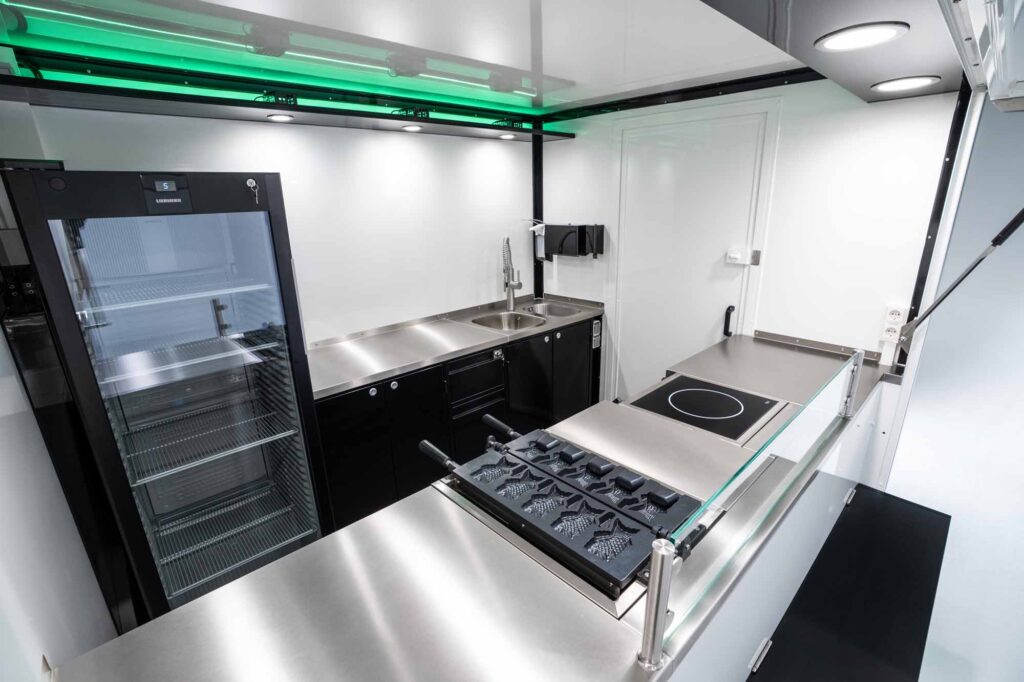 Detailansicht der Küchenausstattung im Kia PV5 Foodtruck mit Kochfeld, Spüle und Kühlgerät.