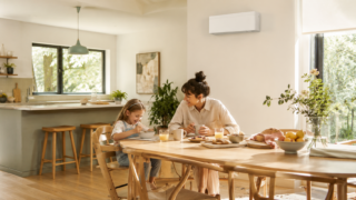 Mutter und Kind frühstücken in einem hellen offenen Wohn- und Essbereich mit wandmontierter Klimaanlage.